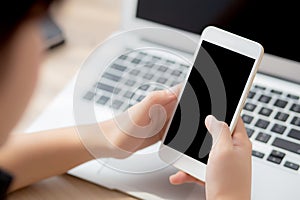 Mockup young businesswoman using smart mobile phone and laptop computer with screen blank on desk