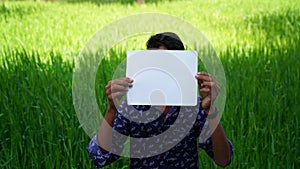 Modal advertisement. Indian Model boy showing a blank white paper in front of Green field for a advertisement company