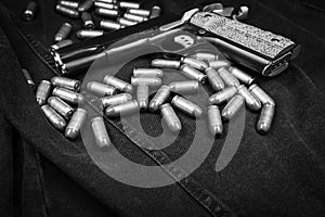 Model 1911 pistol and cartridges (.45 ACP) on a black denim background, monochrome photo