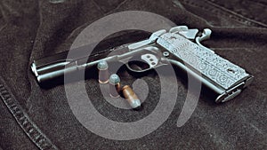 Model 1911 pistol and three cartridges (.45 ACP) on a black denim background