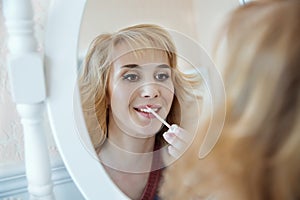 Model applying make up and reflecting in the mirror