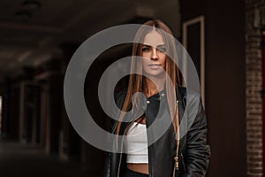 Model of an attractive young woman with beautiful natural makeup in a vintage leather jacket in a stylish white blouse with brown