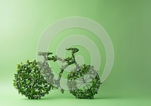 Model of bicycle made of leaves and plants against a green wall. Earth Day and Environmentalism concept