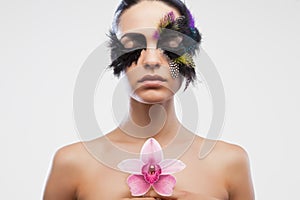 A model with bird feather false eyelashes holds a lotus flower creative makeup