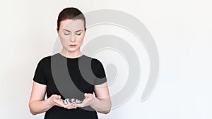 a model in a black T-shirt holds pills and capsules in blisters in her hands. Shot on a white background, place for text.