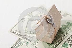 Model of cardboard house with key and dollar bills. House building, loan, real estate, cost of housing or buying a new home concep