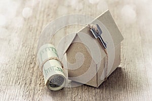 Model of cardboard house with key and dollar bills. House building, loan, real estate, cost of housing or buying a new home concep