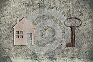 model of cardboard house with key on old textured paper background