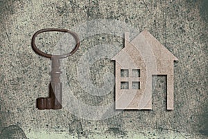 model of cardboard house with key on old textured paper background