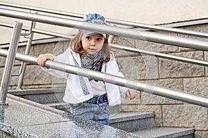 Model child girl hip hop on the stairs outdoors.children`s street fashion denim