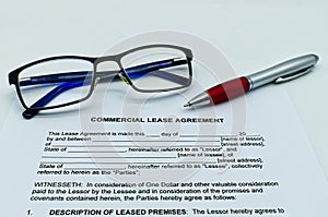 Model of commercial lease agreement on a white table, with glasses and pen