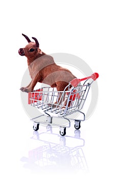 Model cow in shopping cart isolated on white