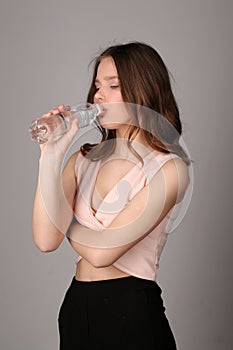 Model drinking water. Close up. Gray background