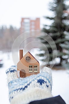 A model of an eco-friendly wooden house in the hands on a winter background