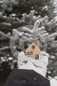 A model of an eco-friendly wooden house in the hands on a winter background