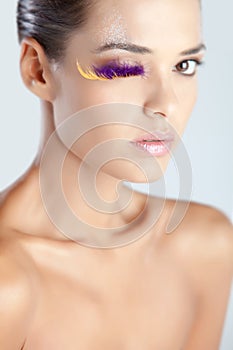 Model with fake eyelashes made of purple feather glittery lips creative makeup