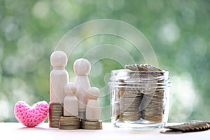 Model family with coins money in the glass bottle on natural green background,Save money for prepare in future and family finance