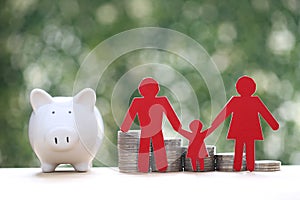 Model family with piggy bank and stack of coins money on natural green background,Save money for prepare in future and family