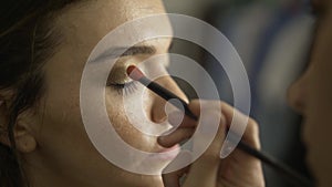 Model with freckles is having her shadows applied