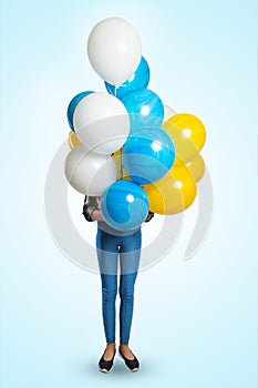 Model girl holds in front of her a bunch of colorful balloons. Covers the face with balloons