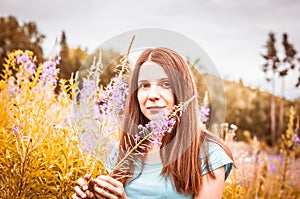 model girl posing on lupine field. Portrait of beautiful woman on autumn field