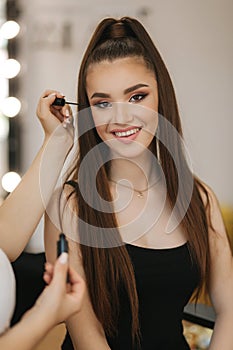 Model have a makeup by makeup artist in beauty salon. First person view. Redhead model with freckles. Close up of model