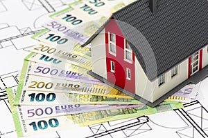 Model home standing on bundles of Euro currency