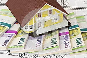Model home standing on bundles of Euro currency