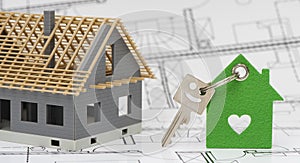 model home standing on construction plan and house key