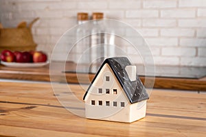 A model of a house on the background of kitchen furniture. The concept of buying a house, real estate mortgage, home interior