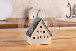 A model of a house on the background of kitchen furniture. The concept of buying a house, real estate mortgage, home interior