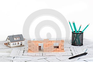 Model house construction with brick on blueprint.
