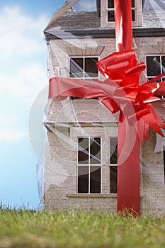 Model house gift-wrapped with red ribbon and bow close-up