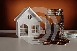 Model of house and glass jar with coins, financial and mortgage concept