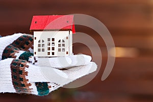 Model of house at hands, outdoors. Protecting and isolating house. Winter. Real estate and property concept. Small miniature of