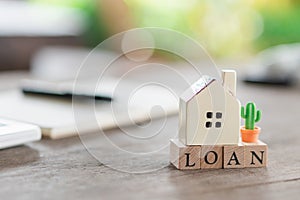 A model house model is placed on a Notebook wood word LOAN using as background business concept and finance concept with copy