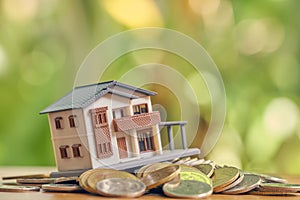 A model house model is placed on a pile of coins.using as background business concept and real estate concept with copy space photo