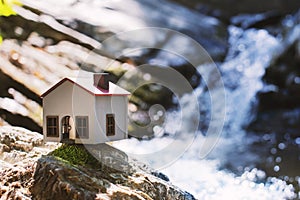 Model house on a rock and there is a waterfall behind it