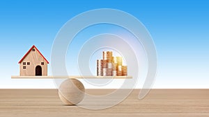 Model house on seesaw balancing with stacking coins money on blue background. Property investment and home mortgage financial real