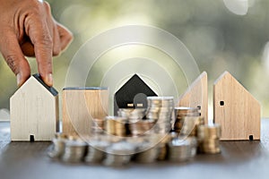 Model of house with stack coins on table on blurred background. Money saving or investing for home loan or real estate. Investment