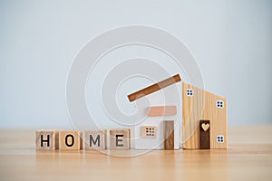 Model house and wood blocks with word HOME wood on table. plan finances investments and savings to buy house real estate.Home on