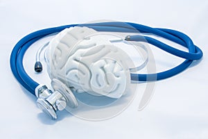 Model of human brain with convolutions and blue stethoscope are on white uniform background. Concept photo health or pathological