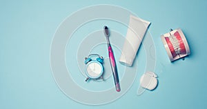 Model of a human jaw with white teeth, dental floss and toothpaste on a blue background