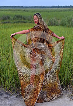 Model in long animal print dress posing at grass field.