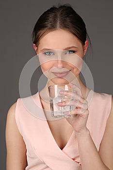 Model with makeup drinking water. Close up. Gray background