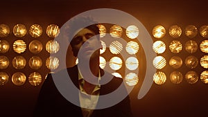 Model man rubbing palms in nightclub light closeup. Brunette guy moving on stage