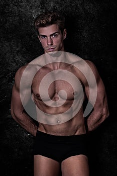 Model man in underwear, black grunge background