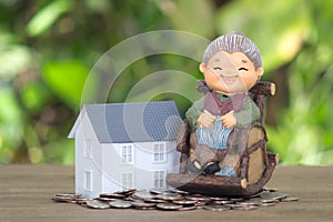 A model of an old woman sitting on a rocking chair and a model of a small house on a pile of dollar coins