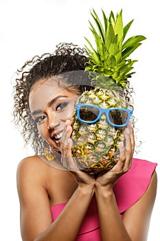 Model with pineapple in hands. African American Girl with Exotic Fruit. Cheerful woman with a smile relaxing on vacation. Image