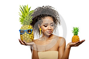 Model with pineapple in hands. African American Girl with Exotic Fruit. Cheerful woman with a smile relaxing on vacation. Image